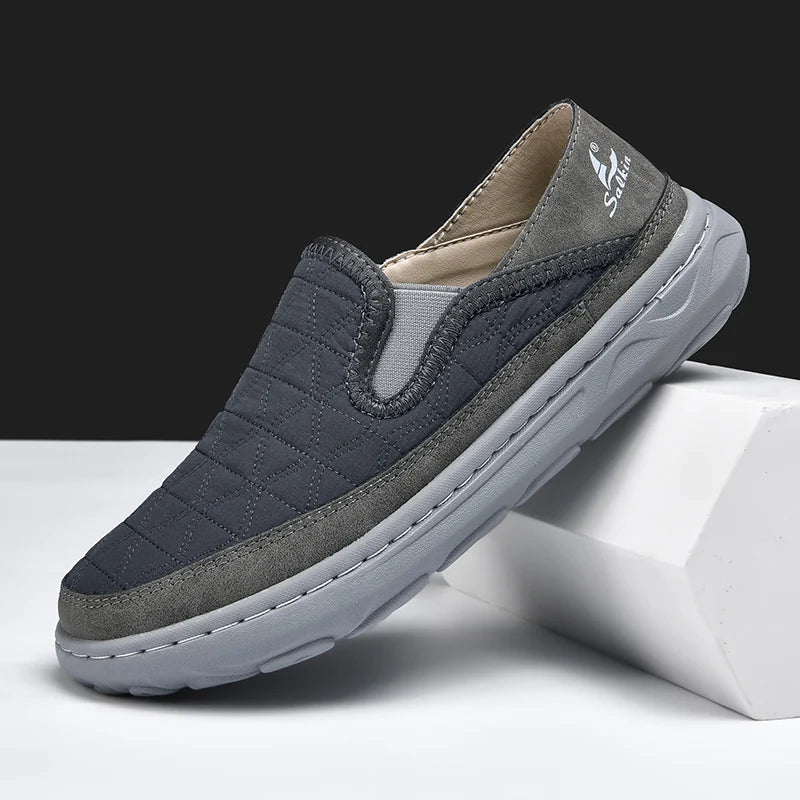 Gray and navy slip-on shoe on a white block with a black background