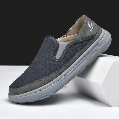 Gray and navy slip-on shoe on a white block with a black background