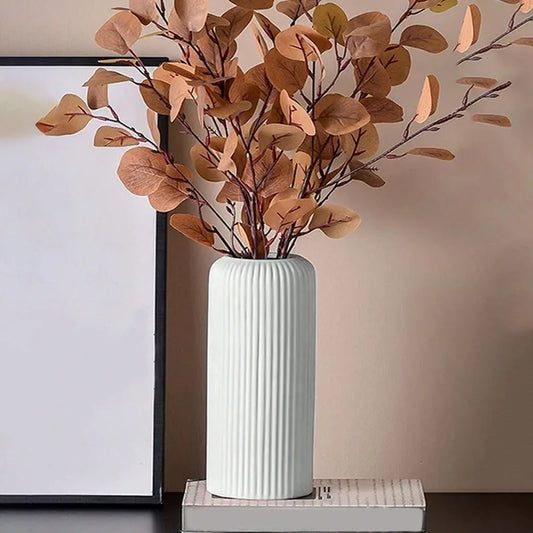 White vase with brown leaves on a neutral background