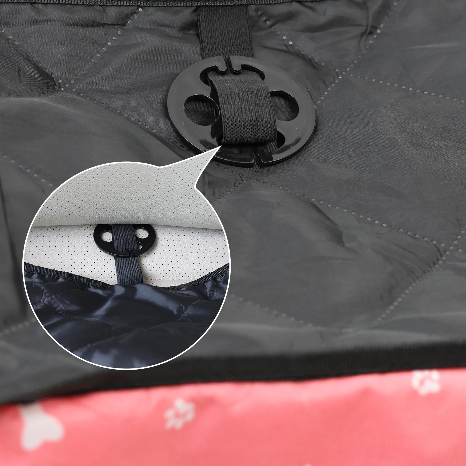 Close-up of a black strap attachment on a gray surface with a red and white patterned object partially visible.