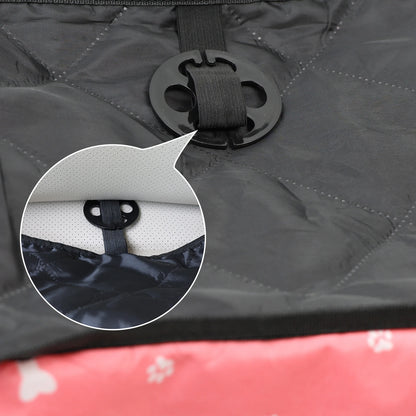 Close-up of a black strap attachment on a gray surface with a red and white patterned object partially visible.