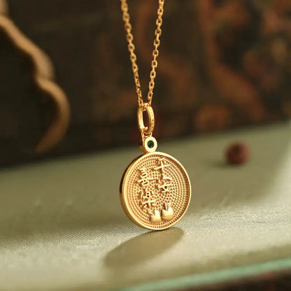 Gold necklace with a round pendant on a textured surface