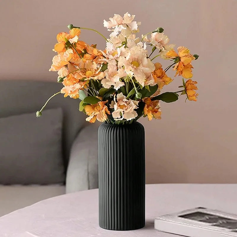 Black vase with flowers on a table against a neutral background