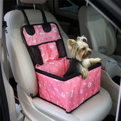 Dog sitting in a pink pet seat cover with bone and paw pattern in a car.
