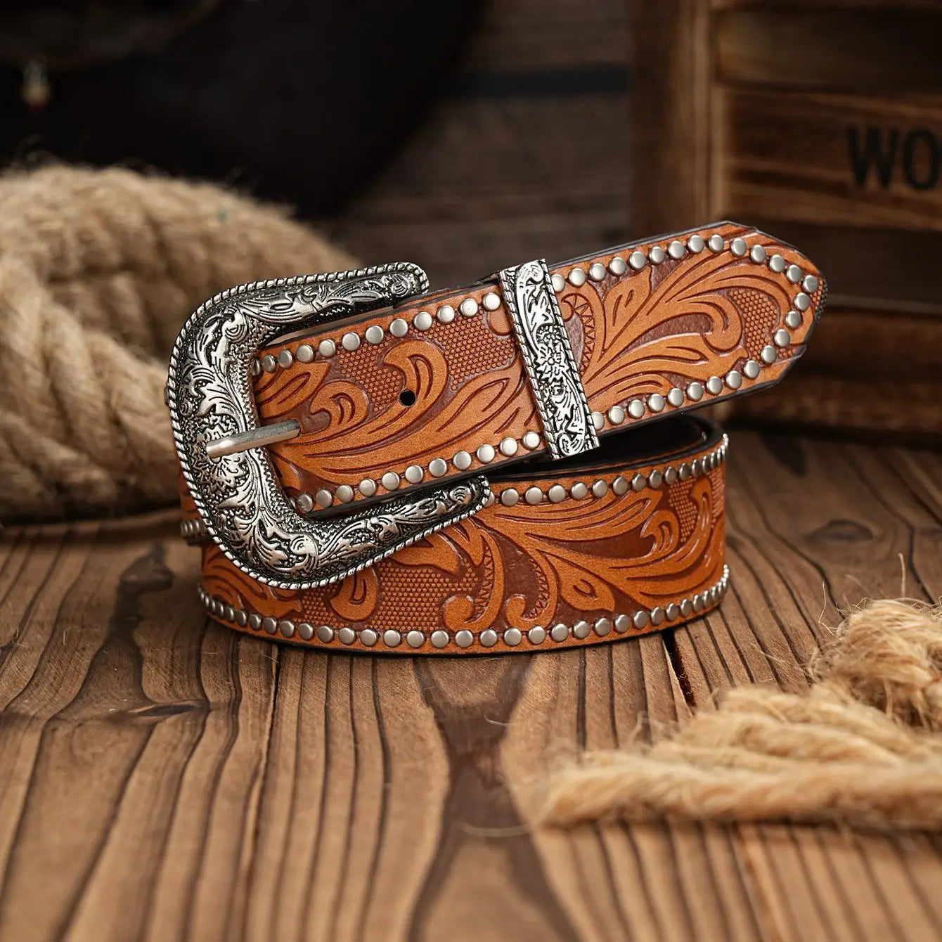 Brown leather belt with silver buckle on a wooden surface