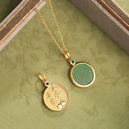 Two gold pendants on a green fabric background