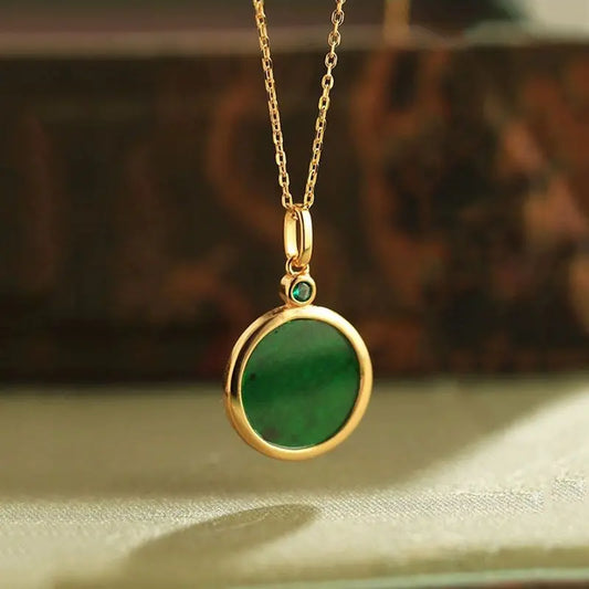 Gold necklace with a green pendant on a textured surface