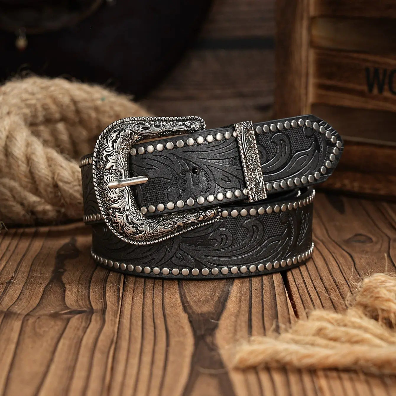Black leather belt with silver buckle on a wooden surface