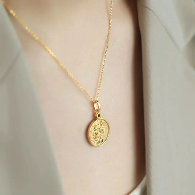 Gold necklace with a pendant on a neutral background